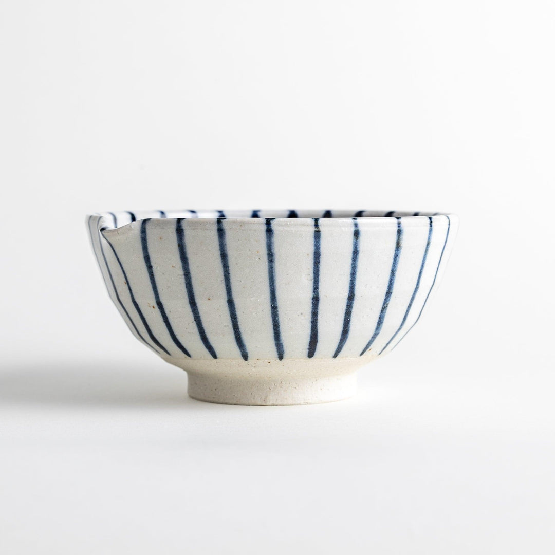 A small, white ceramic bowl with blue vertical stripes on the exterior and a dark brown, textured interior.