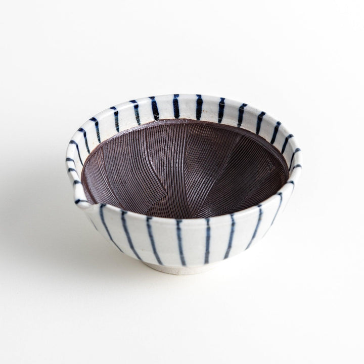 A small, white ceramic bowl with blue vertical stripes on the exterior and a dark brown, textured interior.