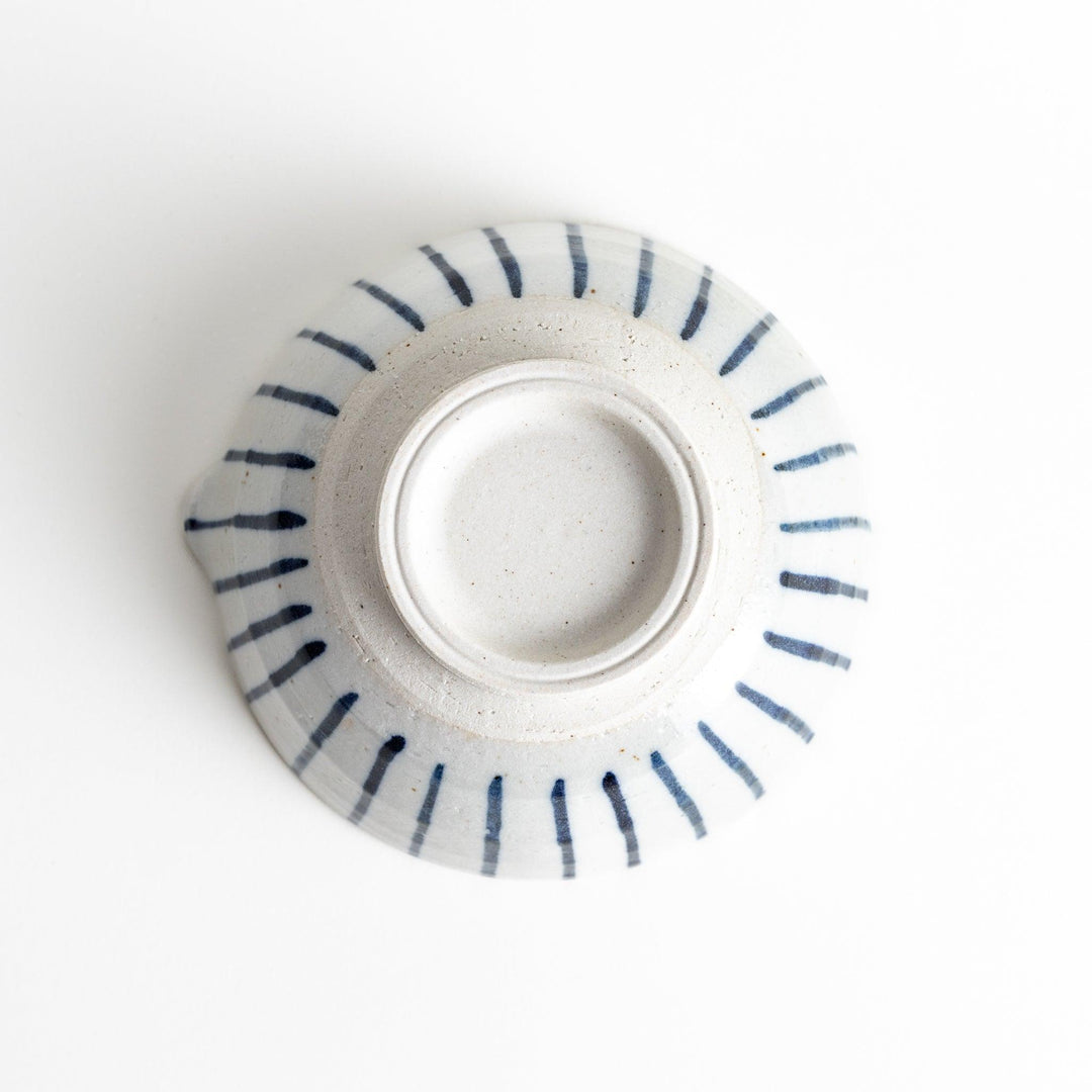 A small, white ceramic bowl with blue vertical stripes on the exterior and a dark brown, textured interior.