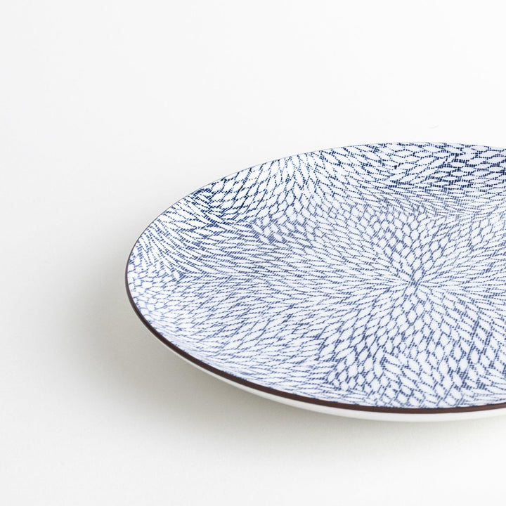 A round dinner plate adorned with a complex blue radial pattern spreading from the center.