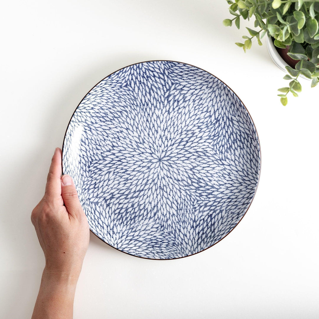 A round dinner plate adorned with a complex blue radial pattern spreading from the center.