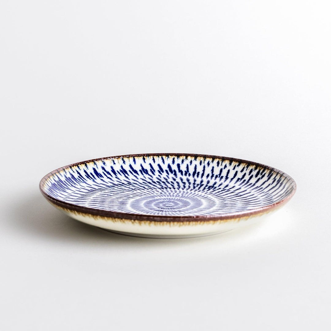 A blue and white salad plate with a concentric spiral pattern/