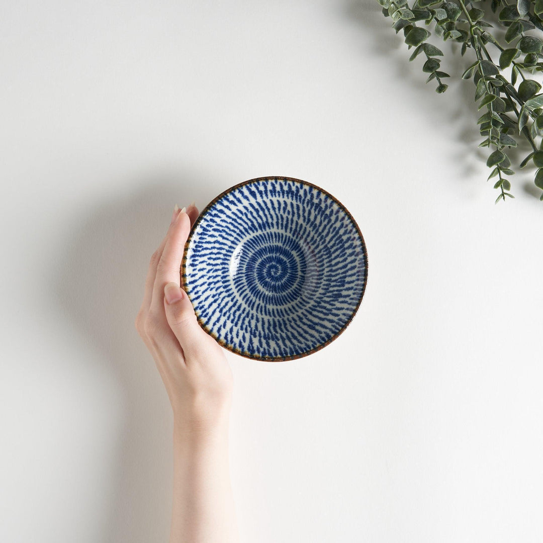 A small, shallow bowl with a flared edge, decorated with blue brushstroke patterns.