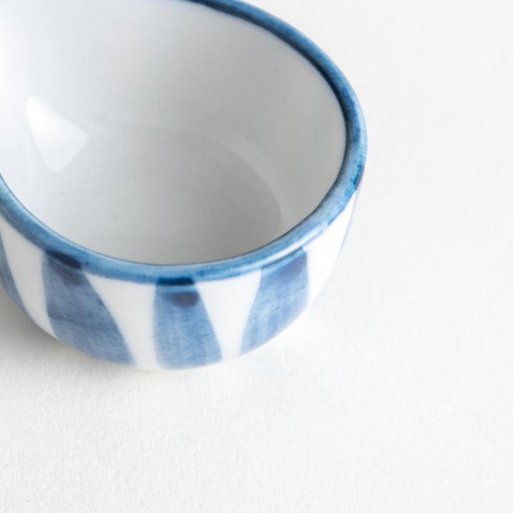 A small condiment bowl with a distinct blue and white vertical stripe pattern.