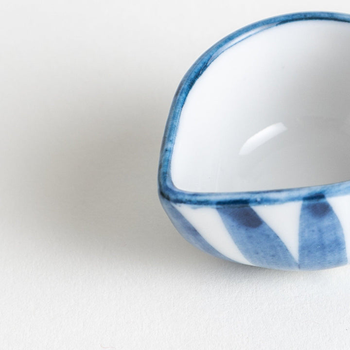 A small condiment bowl with a distinct blue and white vertical stripe pattern.