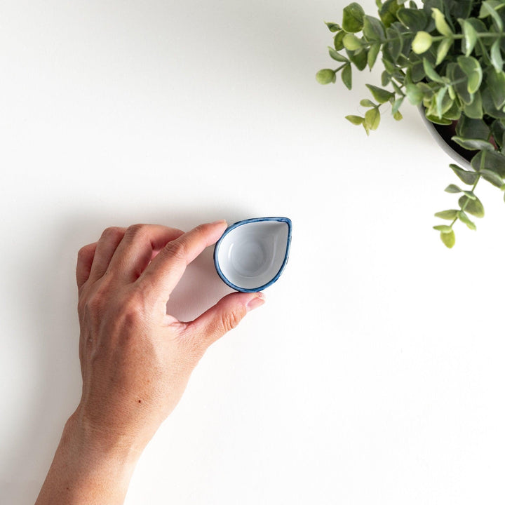 A small condiment bowl with a distinct blue and white vertical stripe pattern.