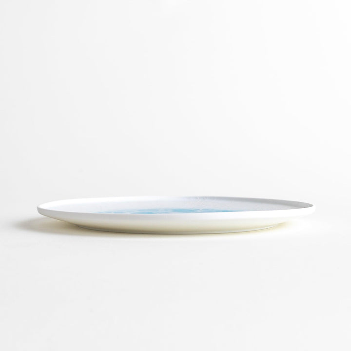 A white salad plate featuring a unique bubble design in shades of blue, resembling frothy ocean waves.