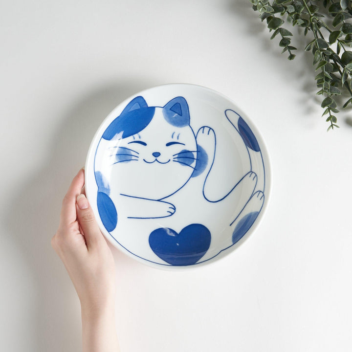 A cereal bowl with a cheerful blue and white cat, playfully kicking its leg up.