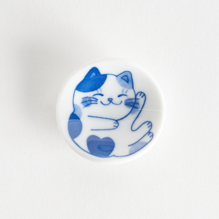 A small chopstick rest with a blue and white cat, playfully stretching one paw upwards.