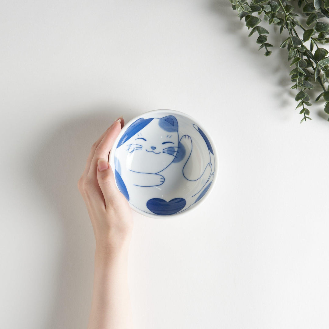 A dessert bowl featuring a playful blue and white cat with a relaxed expression.