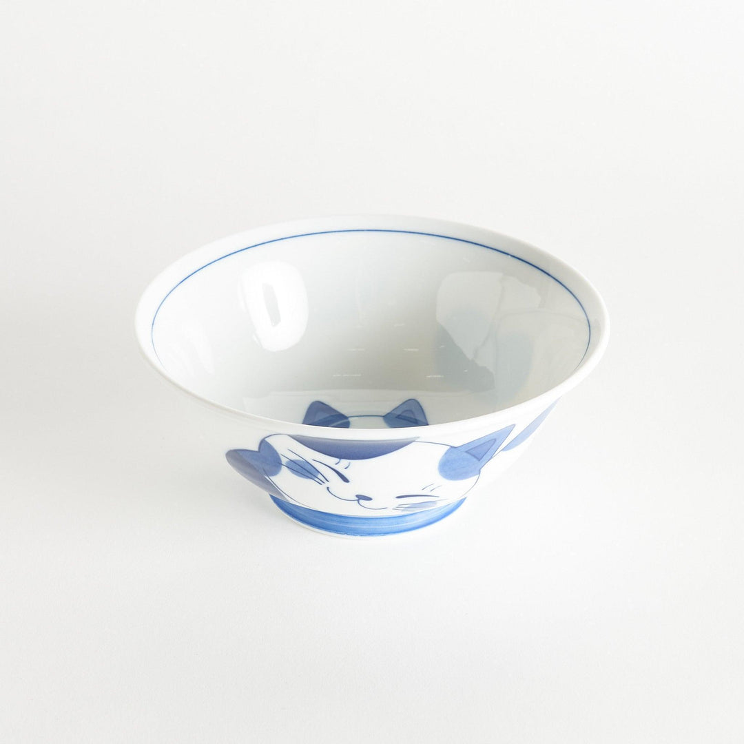 A white ramen bowl with a blue design of a cat with its ears back, looking relaxed.