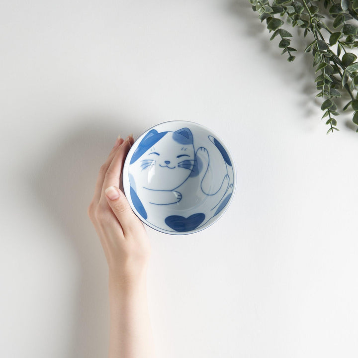 A rice bowl featuring a playful blue and white cat, stretching with a happy expression.