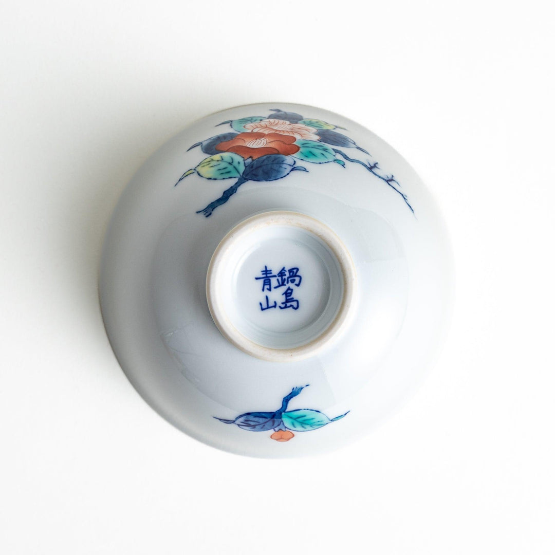 A small, white ceramic rice bowl with a colorful floral design in red, blue, and green.