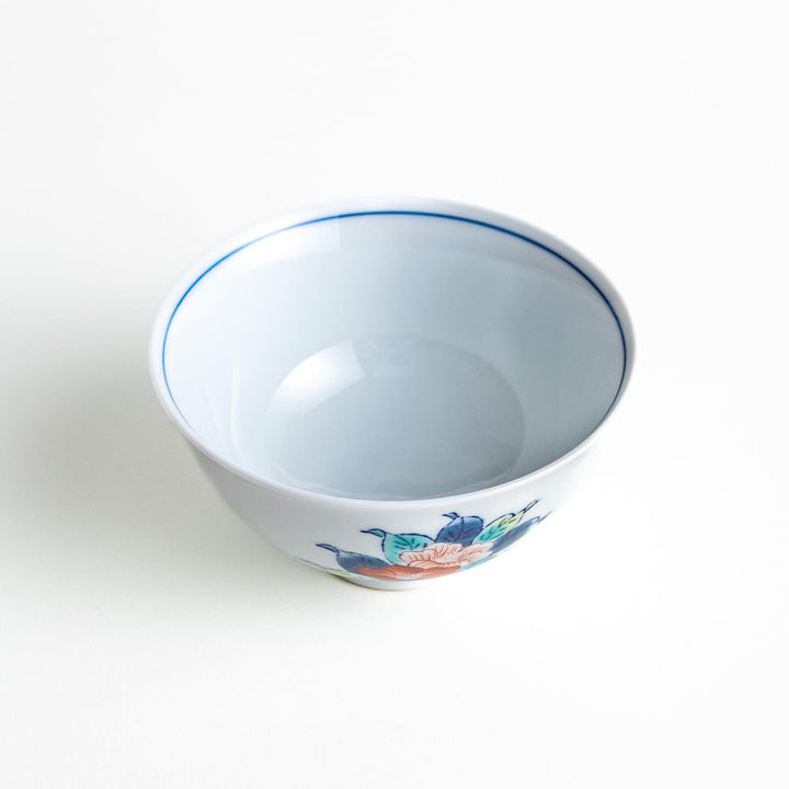 A small, white ceramic rice bowl with a colorful floral design in red, blue, and green.