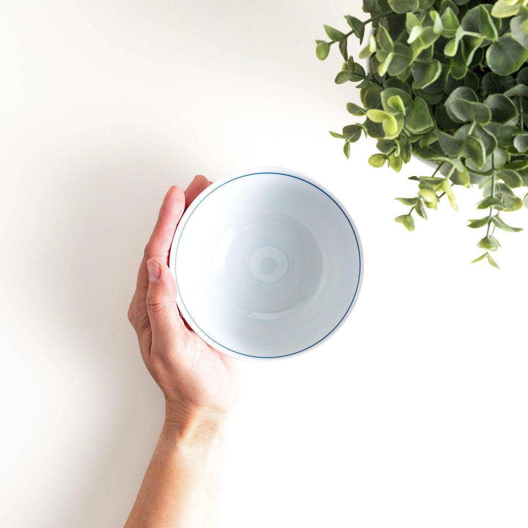 A small, white ceramic rice bowl with a colorful floral design in red, blue, and green.