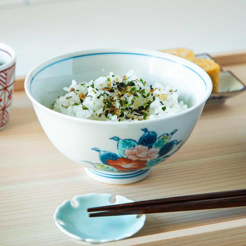 A small, white ceramic rice bowl with a colorful floral design in red, blue, and green.