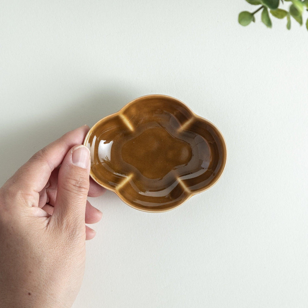 A small, brown ceramic dish shaped like a quince.