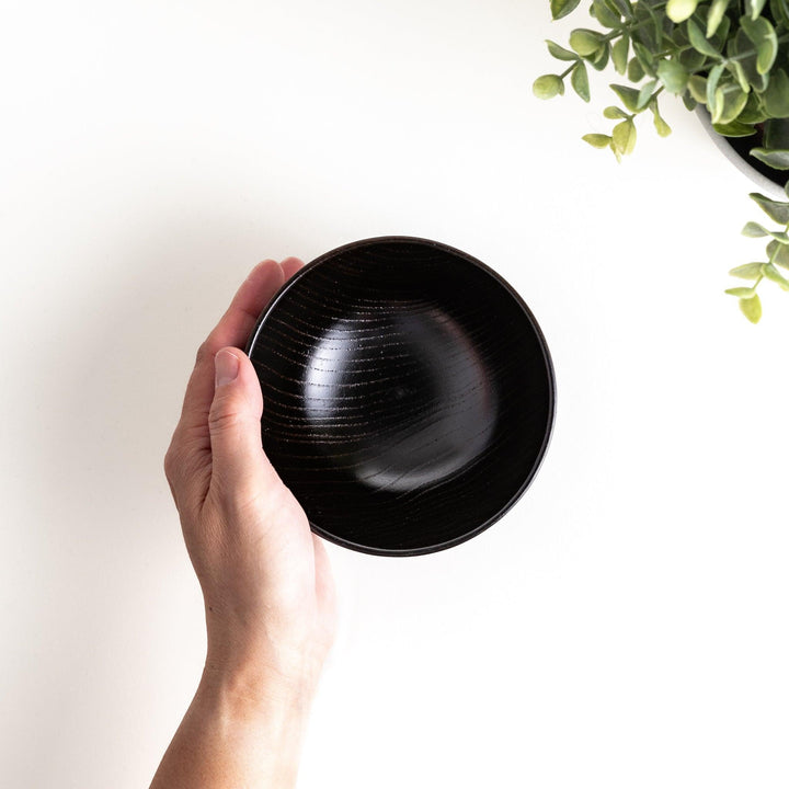 A traditional lacquered wooden bowl featuring a hand-carved pattern of lines and geometric shapes. Available in black or red.