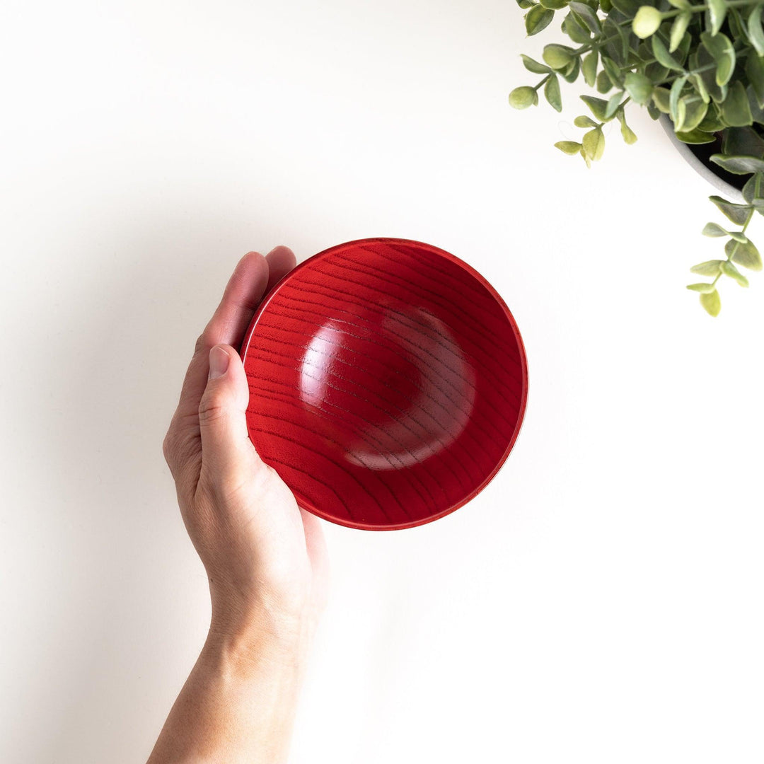 A traditional lacquered wooden bowl featuring a hand-carved pattern of lines and geometric shapes. Available in black or red.