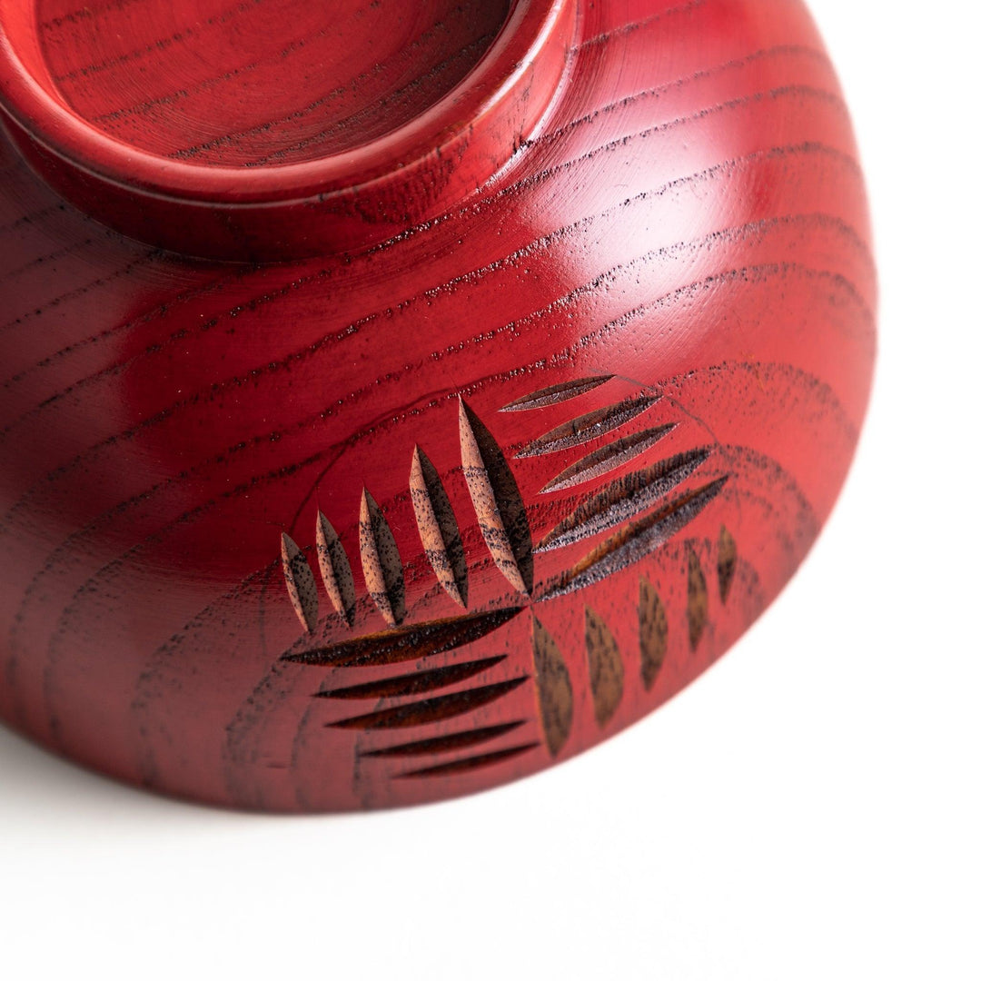 A traditional lacquered wooden bowl featuring a hand-carved pattern of lines and geometric shapes. Available in black or red.