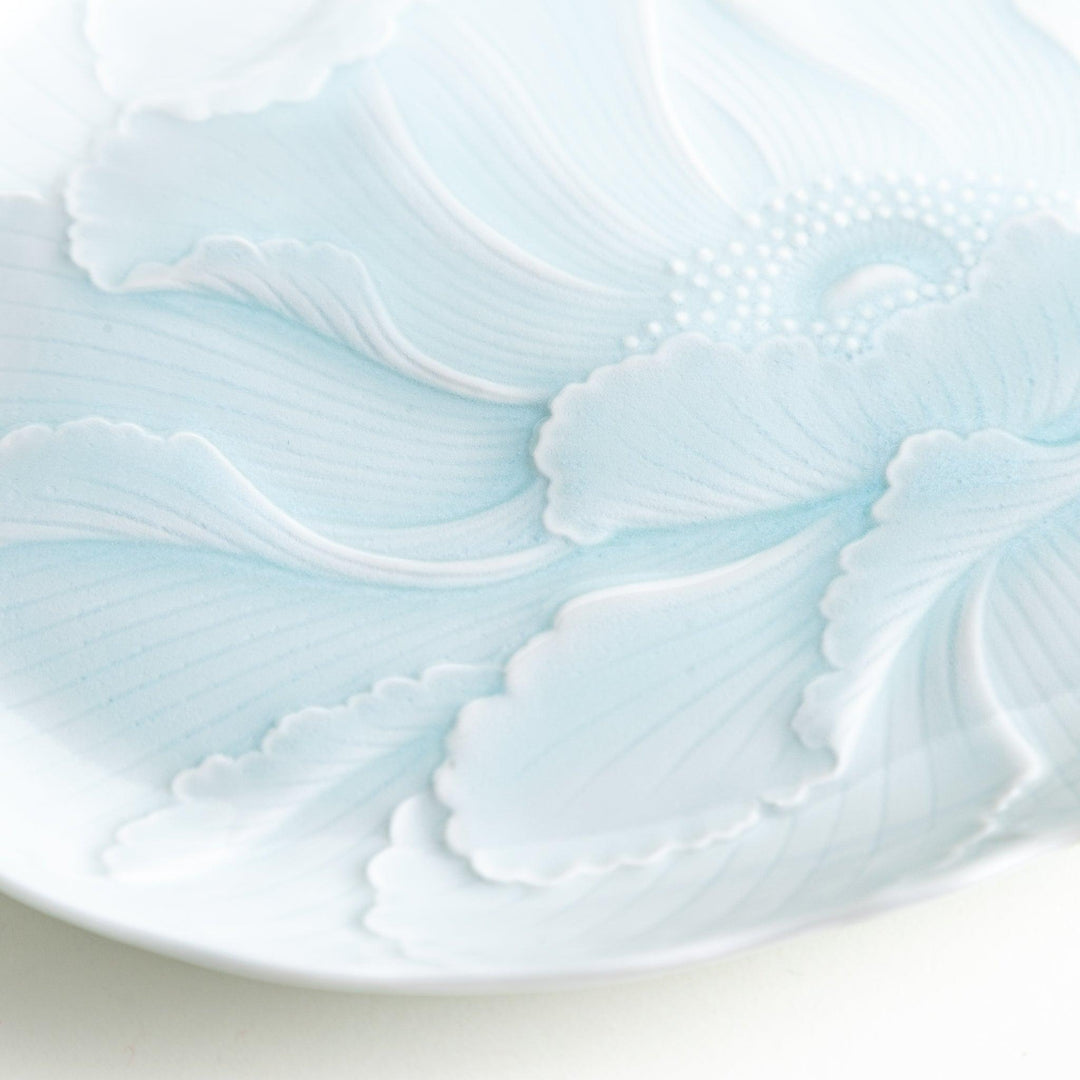 A large oval serving plate with a subtle raised floral design in celadon, featuring a delicate pattern of petals.