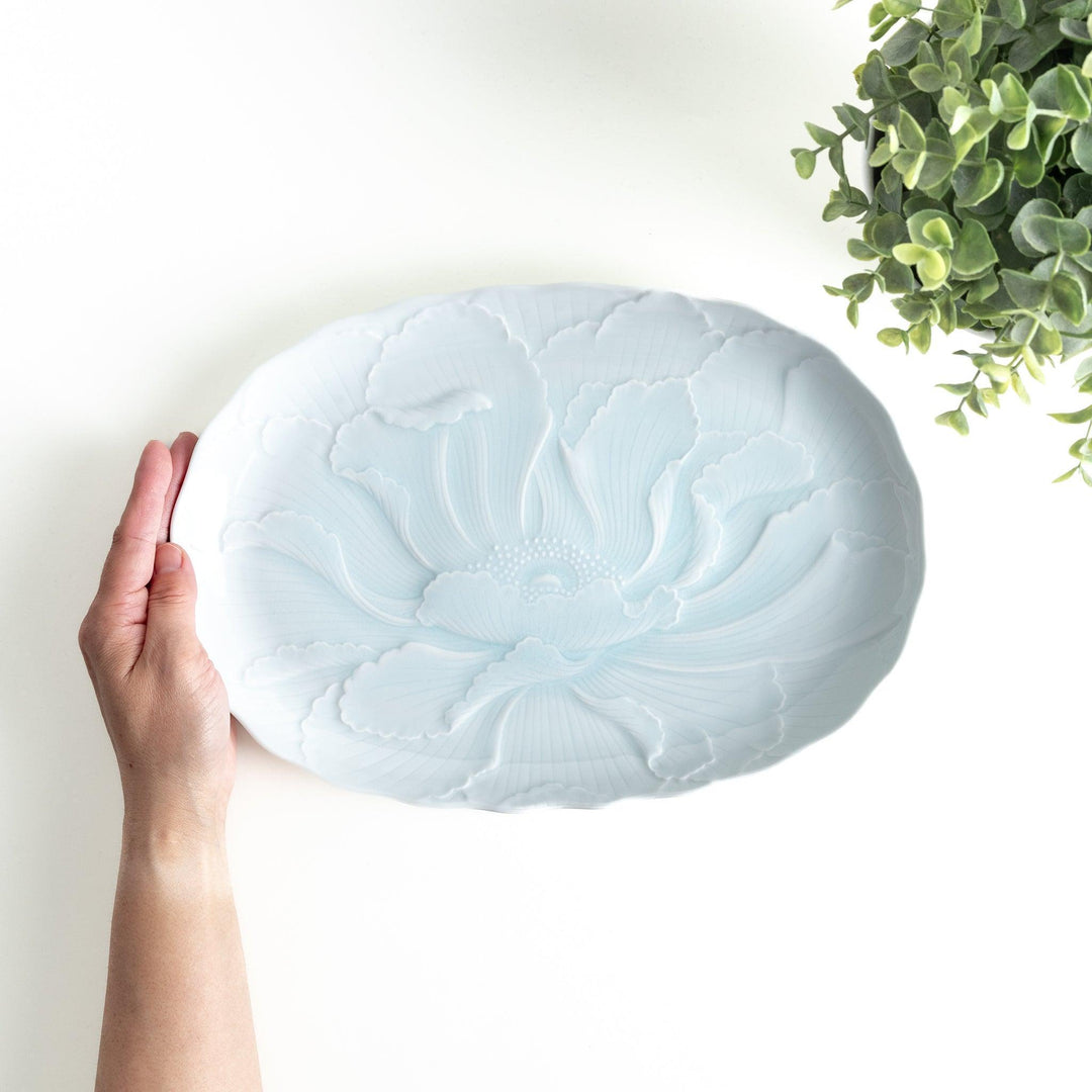 A large oval serving plate with a subtle raised floral design in celadon, featuring a delicate pattern of petals.