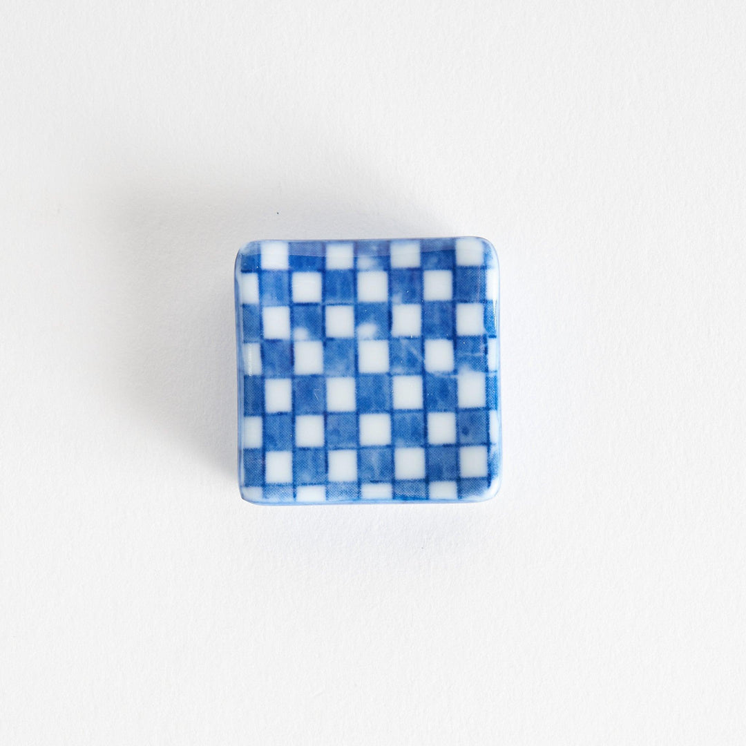 A blue and white checkered square-shaped ceramic chopstick rest.