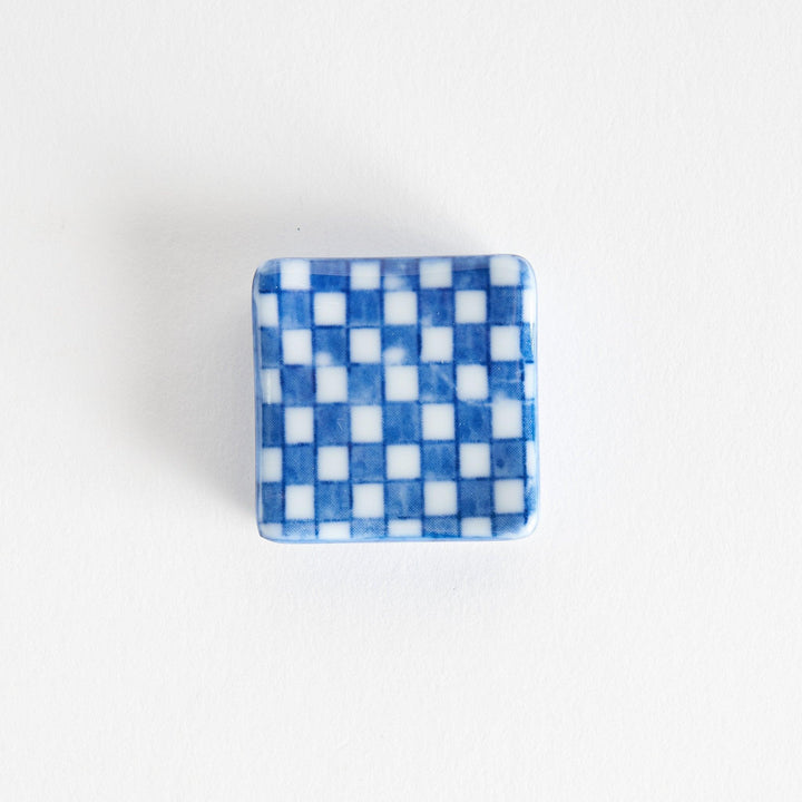 A blue and white checkered square-shaped ceramic chopstick rest.