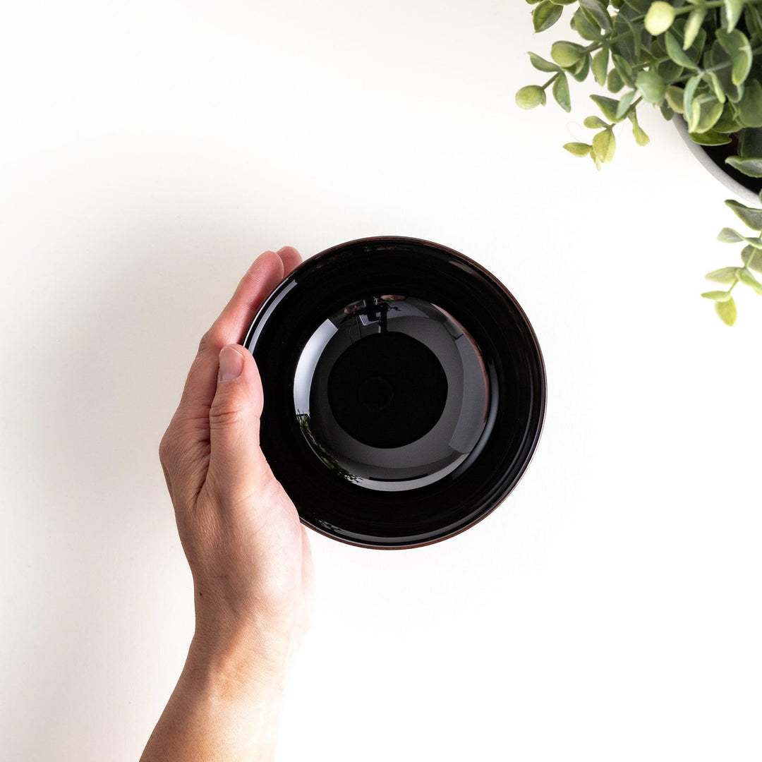 A wooden soup bowl featuring a dark brown grain finish with a sleek black interior.