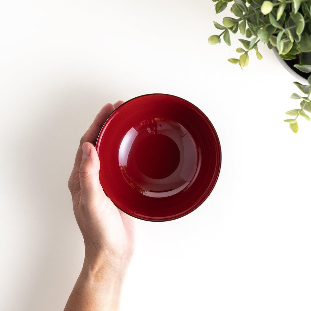 A wooden soup bowl with a rich, brown grain finish and a deep red interior.