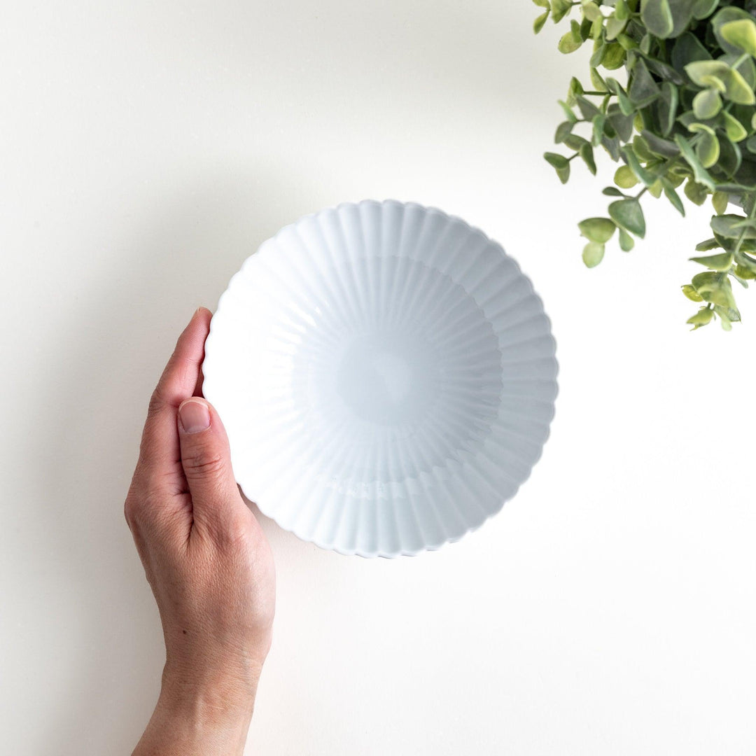 A white ceramic bowl with a delicate scalloped pattern radiating from the center.