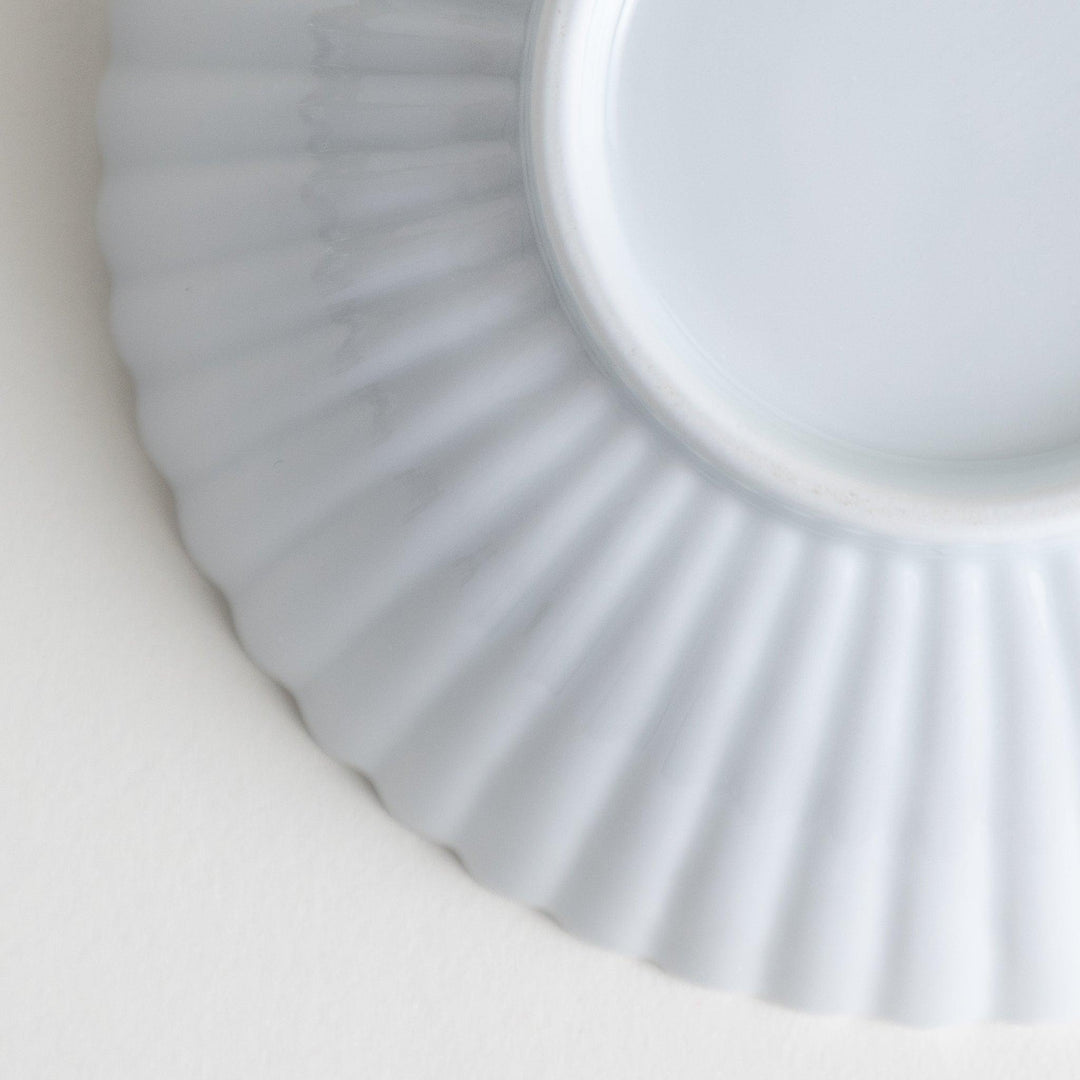 A white ceramic bowl with a delicate scalloped pattern radiating from the center.