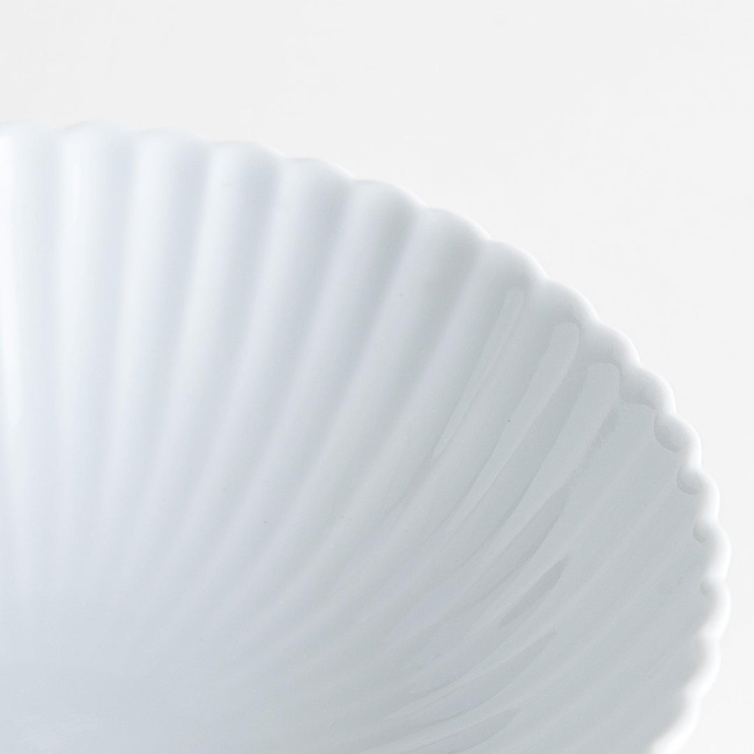 A white ceramic bowl with a delicate scalloped pattern radiating from the center.