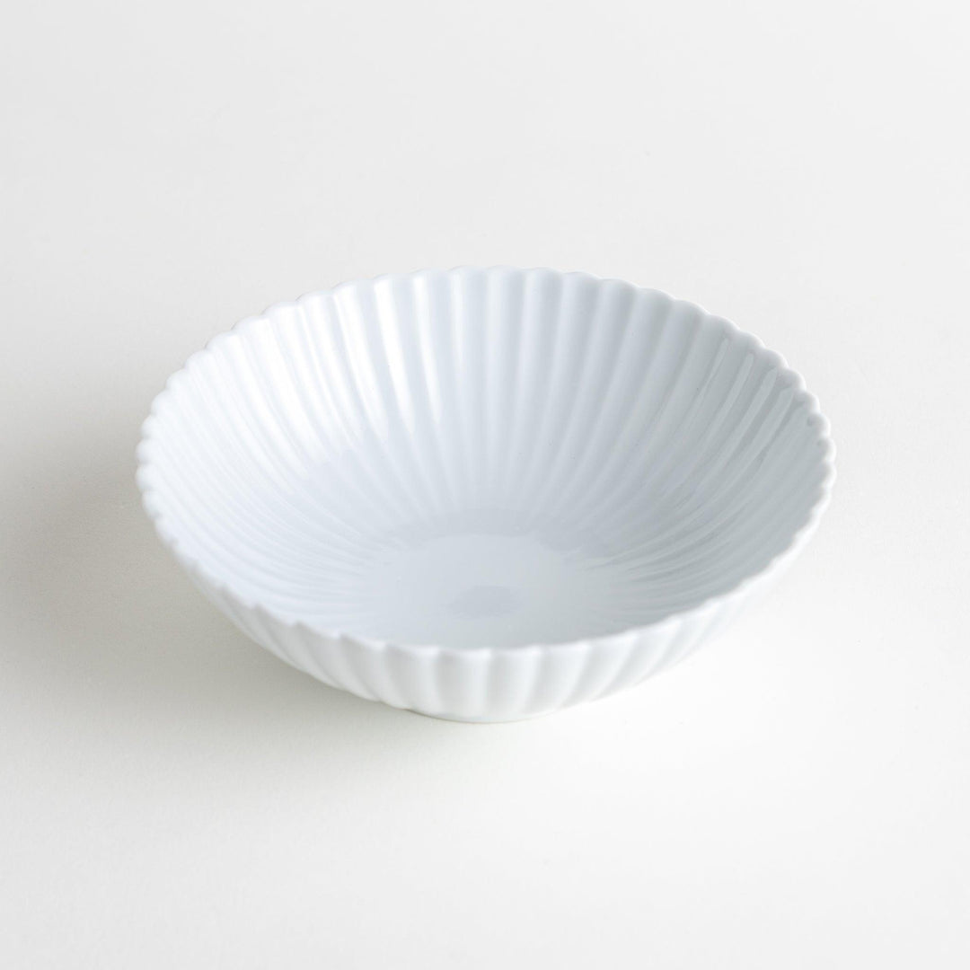 A white ceramic bowl with a delicate scalloped pattern radiating from the center.