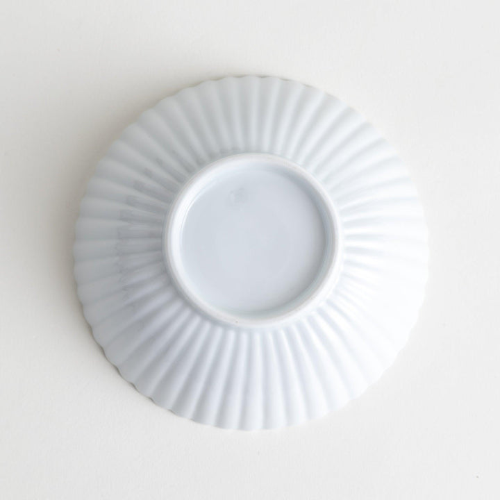 A white ceramic bowl with a delicate scalloped pattern radiating from the center.