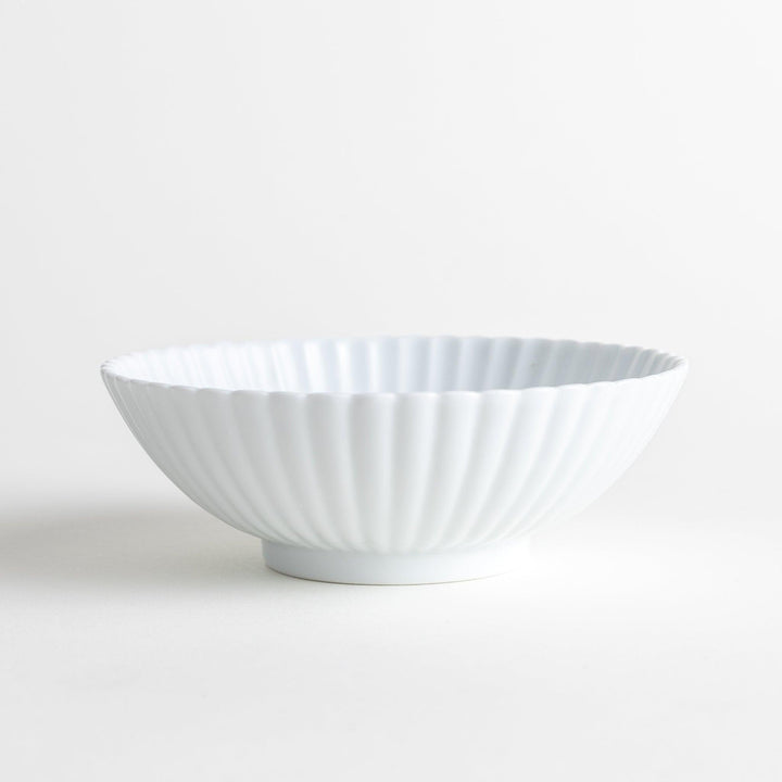 A white ceramic bowl with a delicate scalloped pattern radiating from the center.