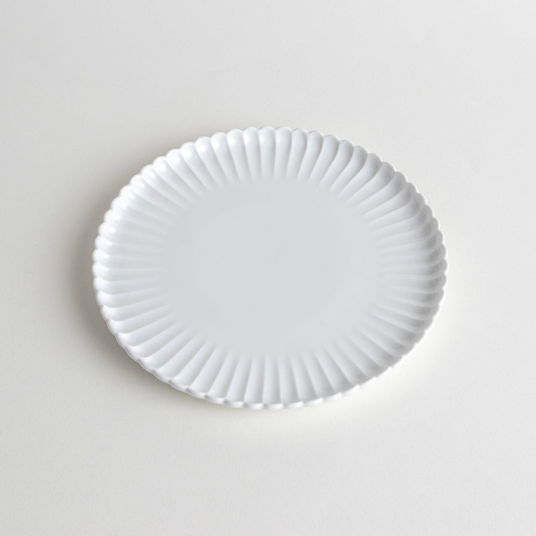 A white ceramic salad plate with a scalloped design with raised edges.