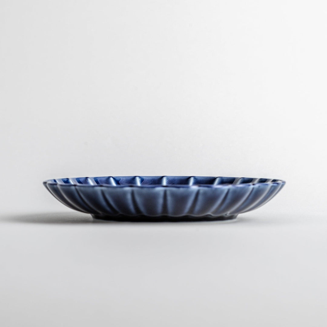 A small, round, blue dish with a ribbed design radiating from the center.