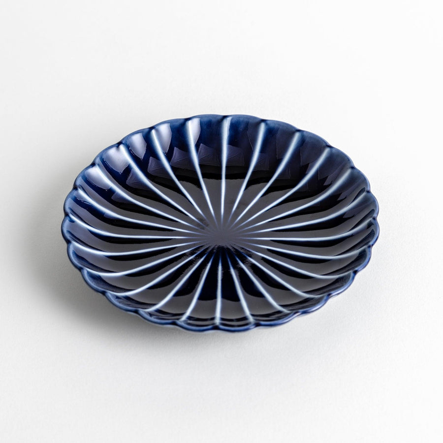 A small, round, blue dish with a ribbed design radiating from the center.