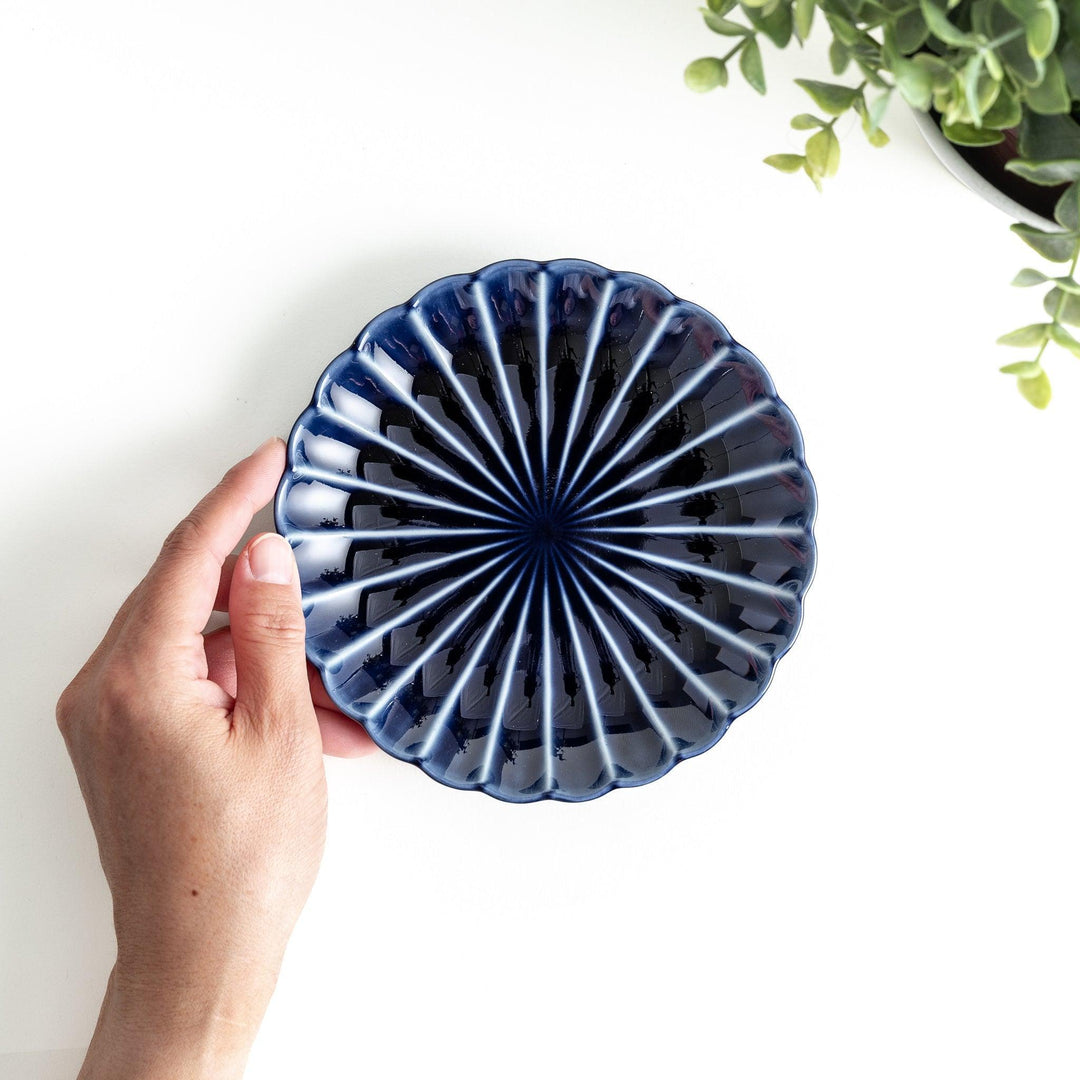 A small, round, blue dish with a ribbed design radiating from the center.