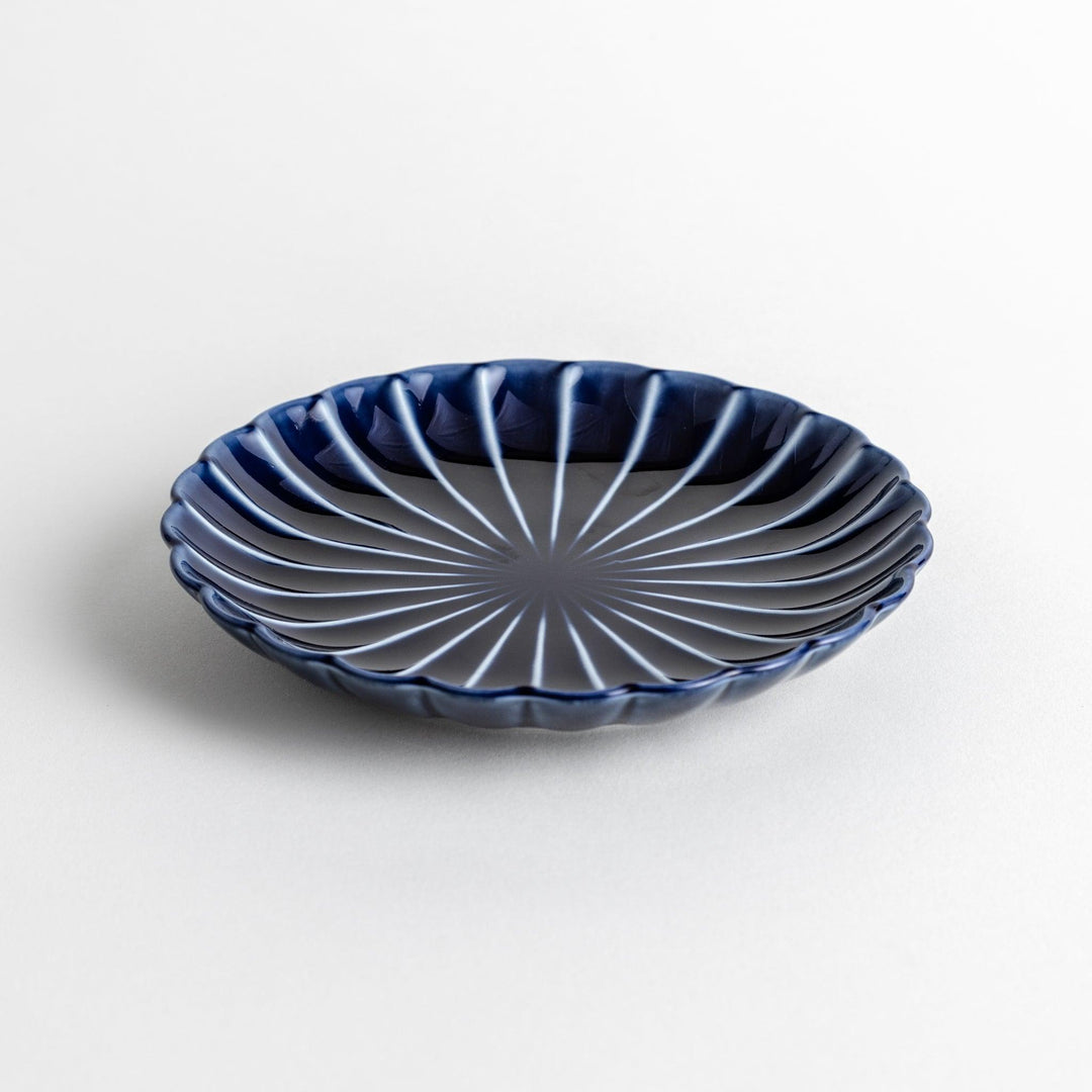 A small, round, blue dish with a ribbed design radiating from the center.