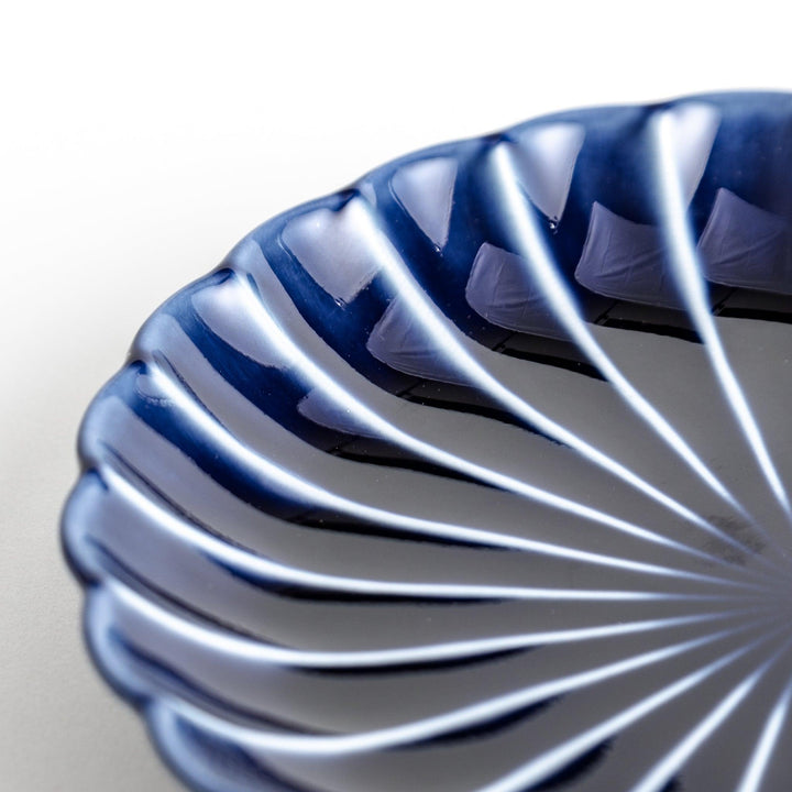 A small, round, blue dish with a ribbed design radiating from the center.