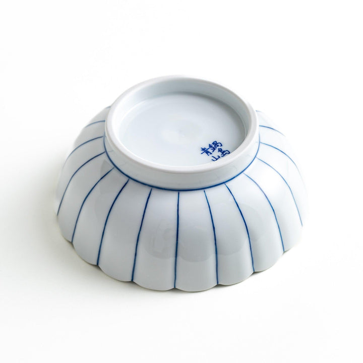 A small green cereal bowl with a scalloped edge and a blue and white wave pattern in the center.