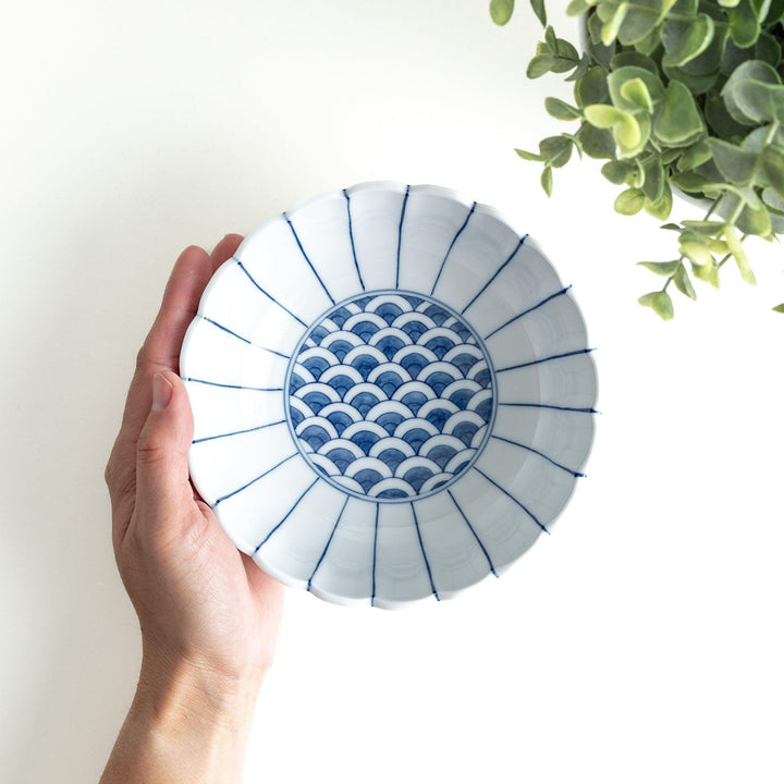 A small green cereal bowl with a scalloped edge and a blue and white wave pattern in the center.