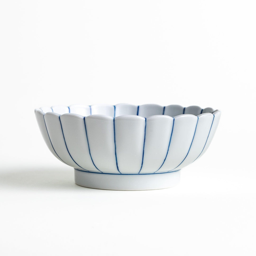 A small green cereal bowl with a scalloped edge and a blue and white wave pattern in the center.