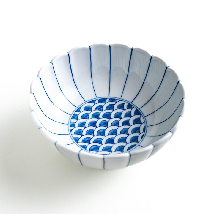 A small green cereal bowl with a scalloped edge and a blue and white wave pattern in the center.