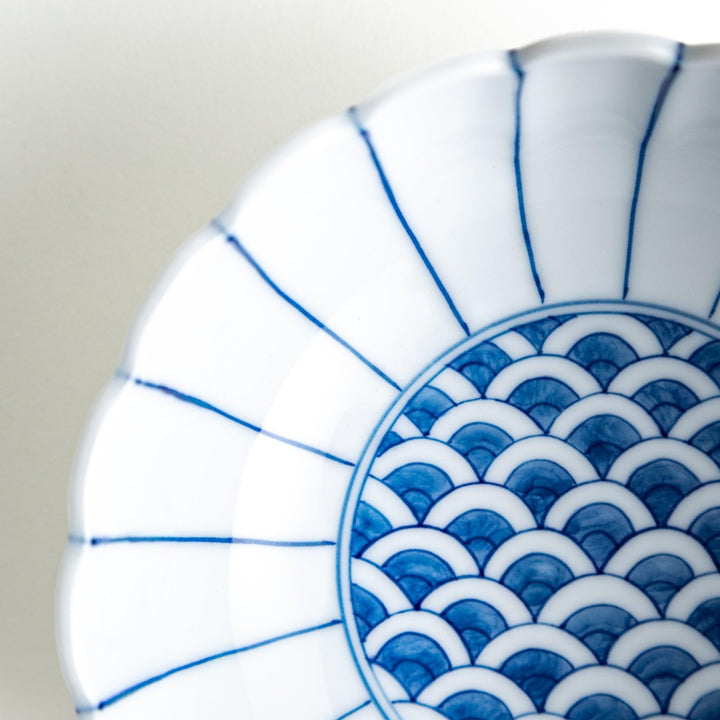 A small green cereal bowl with a scalloped edge and a blue and white wave pattern in the center.