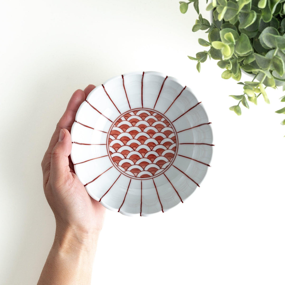 A small green cereal bowl with a scalloped edge and a blue and white wave pattern in the center.