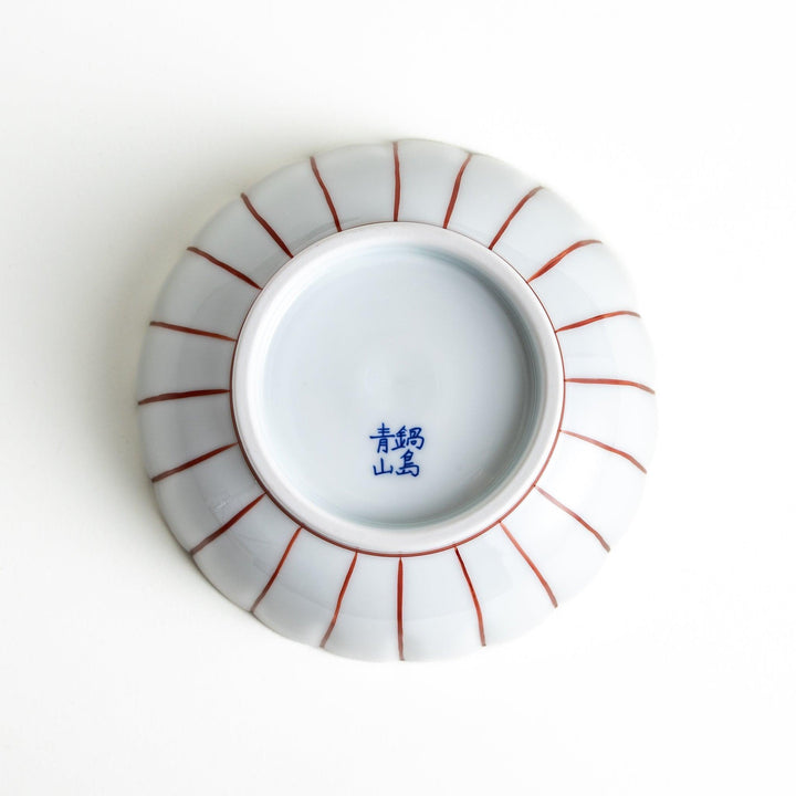 A small green cereal bowl with a scalloped edge and a blue and white wave pattern in the center.