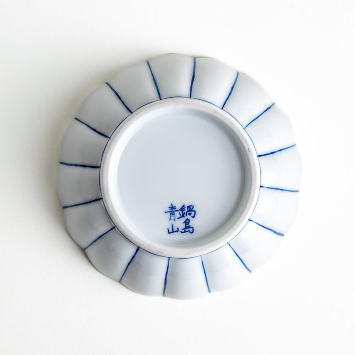 A small green dessert bowl with a scalloped edge and a blue and white wave pattern in the center.